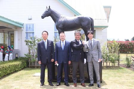 　キズナ像の前で記念撮影に収まる左から前田幸治会長、前田晋二氏、佐々木師、武豊