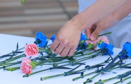 　メイショウカラーの青とピンクの花を手向ける騎手たち（撮影・石湯恒介）