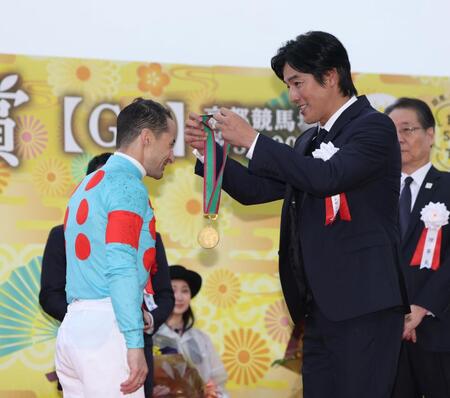 　１１Ｒ、菊花賞を制したクリストフ・ルメール（左）にメダルを贈呈する要潤（撮影・中田匡峻）