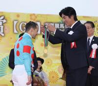 　１１Ｒ、菊花賞を制したクリストフ・ルメール（左）にメダルを贈呈する要潤（撮影・中田匡峻）