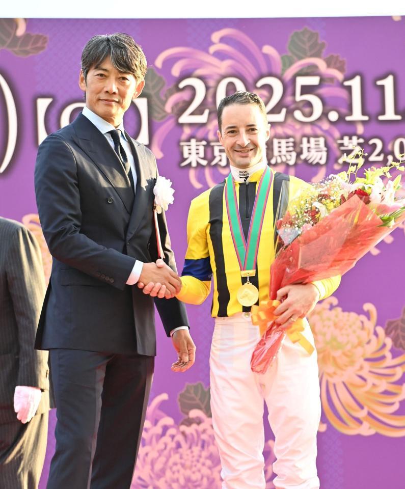 　天皇賞を制しプレゼンターの反町隆史（左）と笑顔で握手を交わすＣ・ルメール（撮影・持木克友）