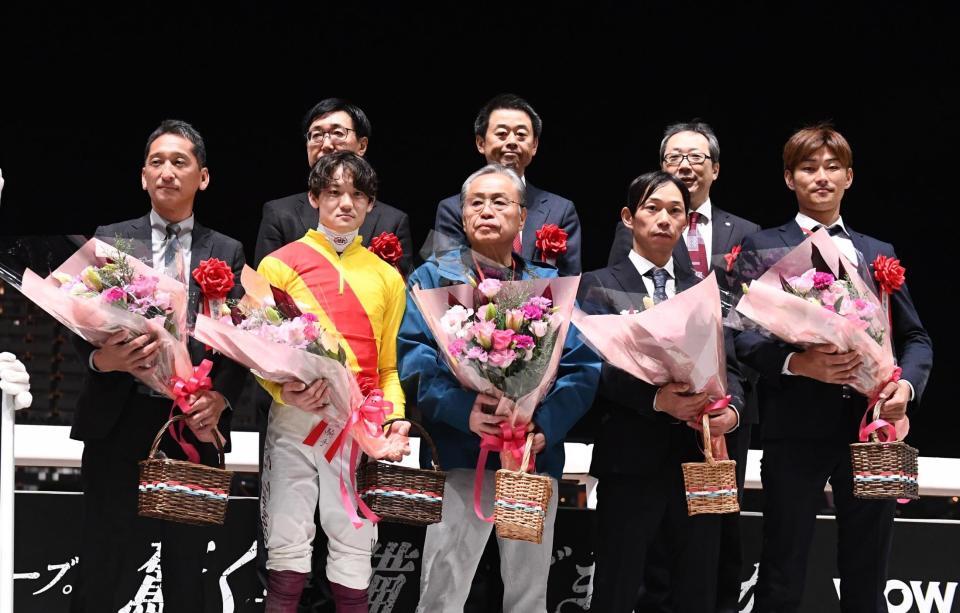 　花束を手にする（前列左から）中道啓二調教師、笹川翼騎手、小川眞査雄氏ら関係者たち（撮影・園田高夫）