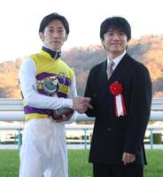 　ニシノティアモで福島記念を制し、プレゼンターの風間俊介と握手する津村（左）