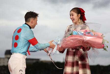 　カヴァレリッツォで朝日杯ＦＳを制したＣ・デムーロ（左）から花束をプレゼントされ驚くゆうちゃみ（撮影・中田匡峻）