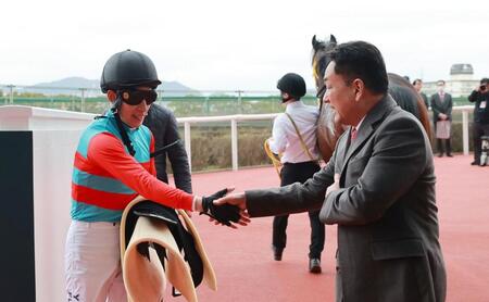 父の藤岡健一師（右）と握手を交わす藤岡佑介＝阪神競馬場（撮影・石湯恒介）
