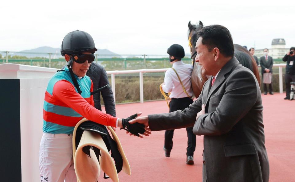 父の藤岡健一師（右）と握手を交わす藤岡佑介＝阪神競馬場（撮影・石湯恒介）
