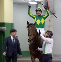 高松宮記念を連覇したサトノレーヴの馬上でガッツポーズするルメール騎手。左は堀調教師