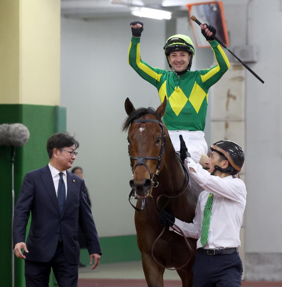 高松宮記念を連覇したサトノレーヴの馬上でガッツポーズするルメール騎手。左は堀調教師