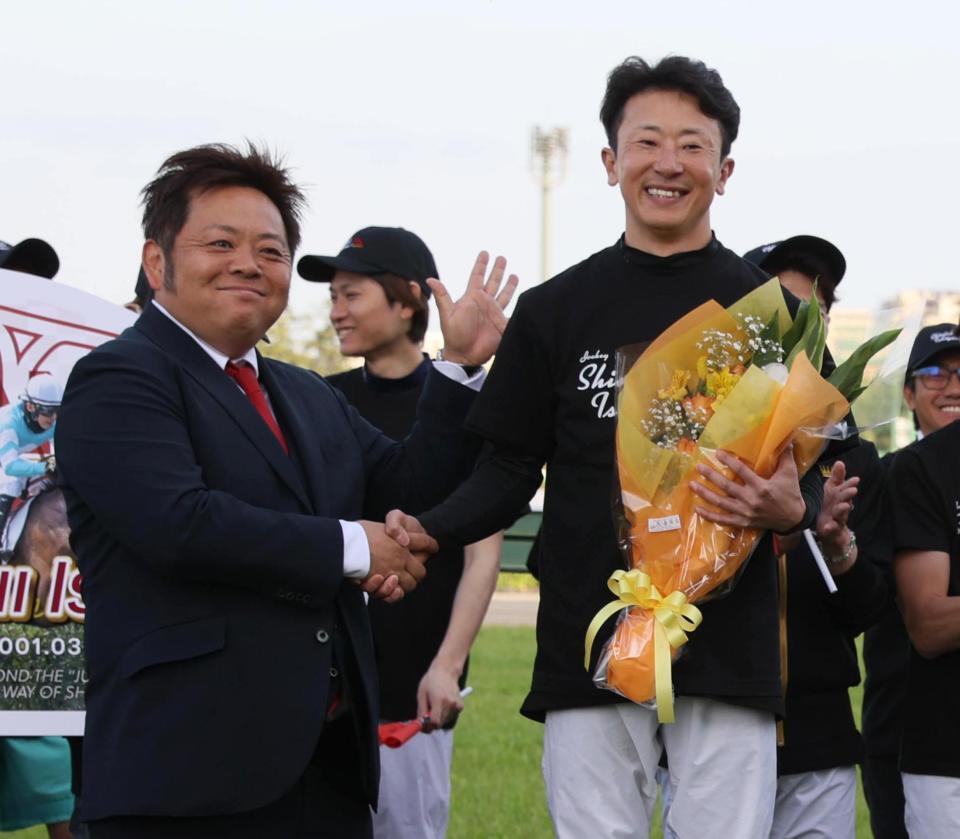 マイネルグロンを管理した青木調教師から花束を贈られ握手する石神深一