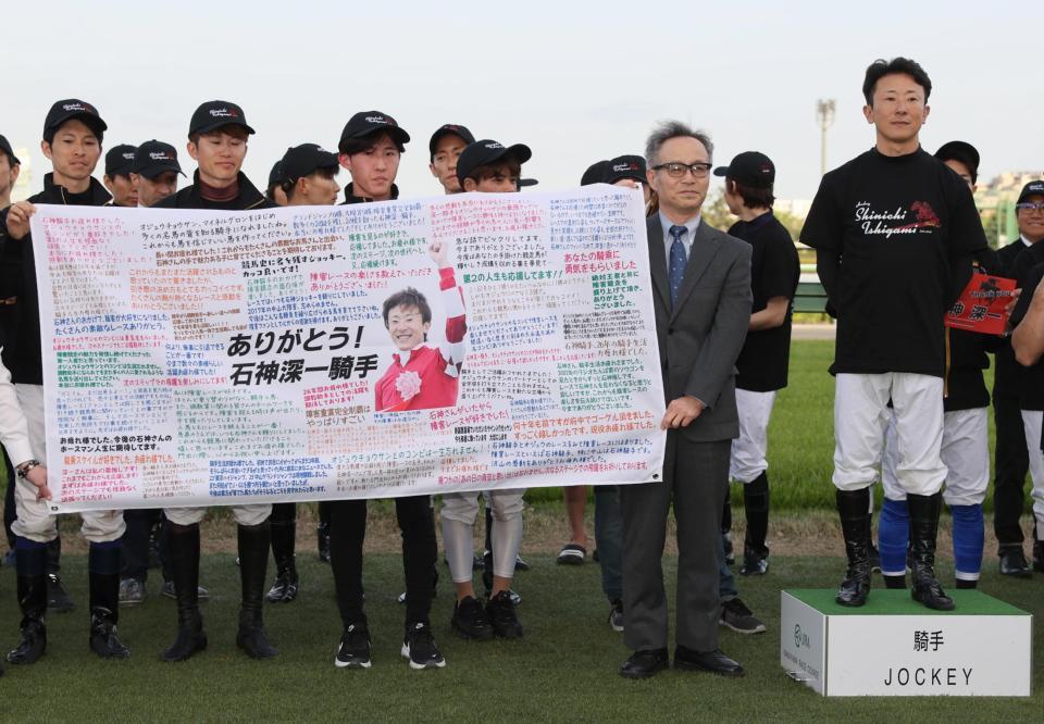 ファンからのメッセージが書かれた横断幕を贈られた石神深一（中央）