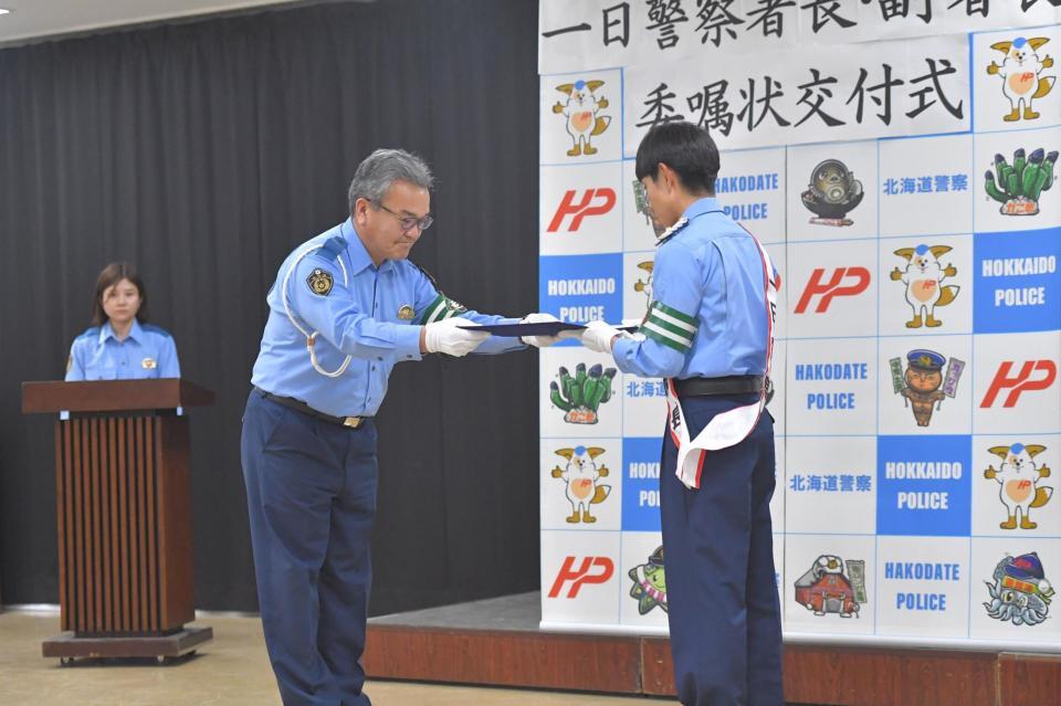 佐藤伸治署長（左）から委任状を受け取る北村友一
