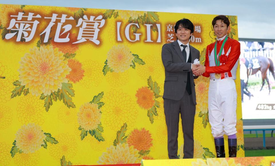 プレゼンターの風間俊介（左）と握手を交わす武豊（撮影・石湯恒介）