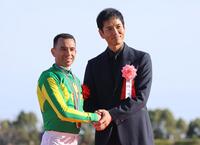 高松宮記念で優勝したモレイラ（左）と握手するプレゼンターの沢村一樹＝３月３０日、中京
